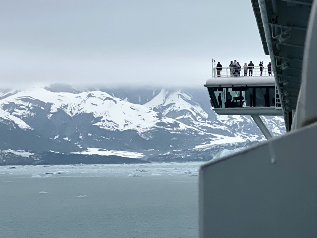 A view of a snowy Alaskan mountain range with tourists viewing the landscape from a watch zone.