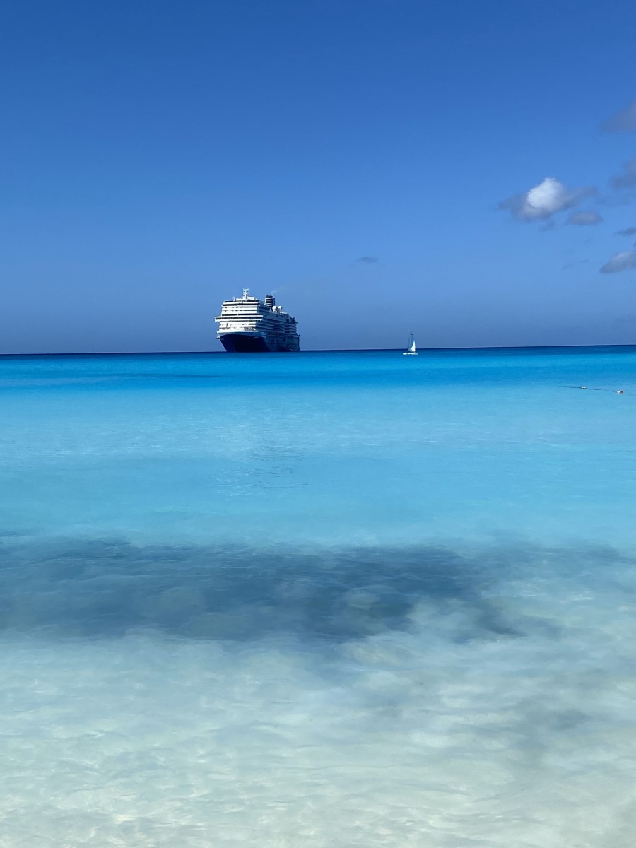 View of a cruise ship sailing away on crystal blue waters.