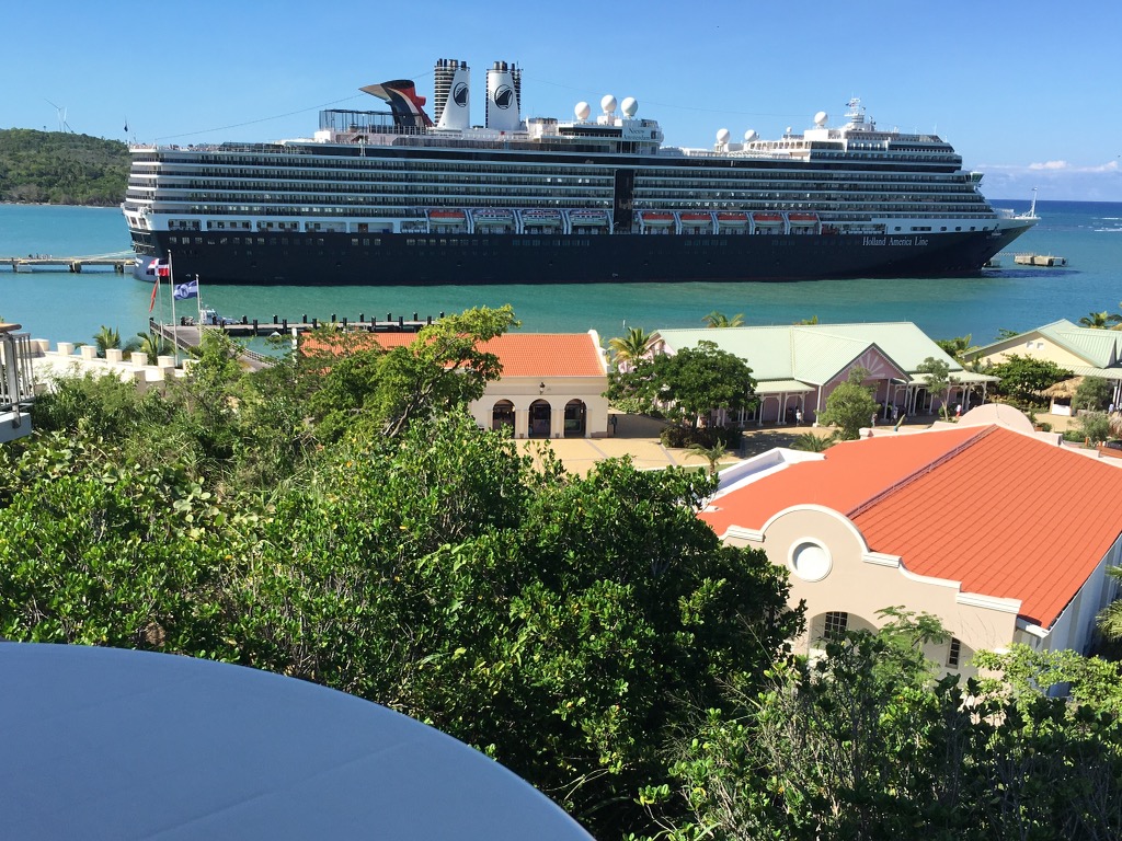 A terrestrial view of a cruise ship on the ocean with many villas surrounded by lush green trees.