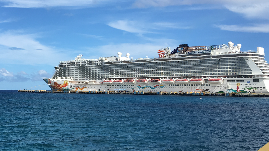 A view of the ncl getaway (a large cruise ship) on the ocean.